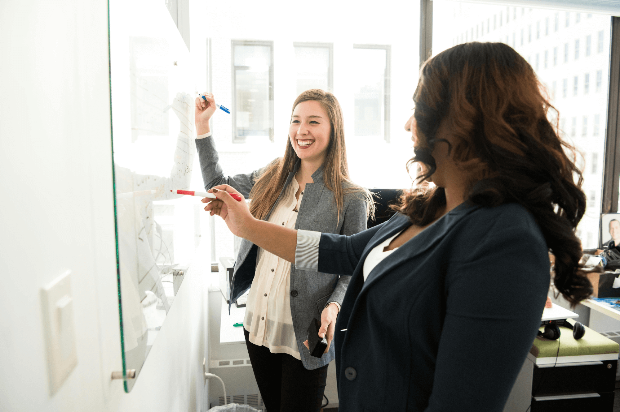 two women writing on a whiteboard